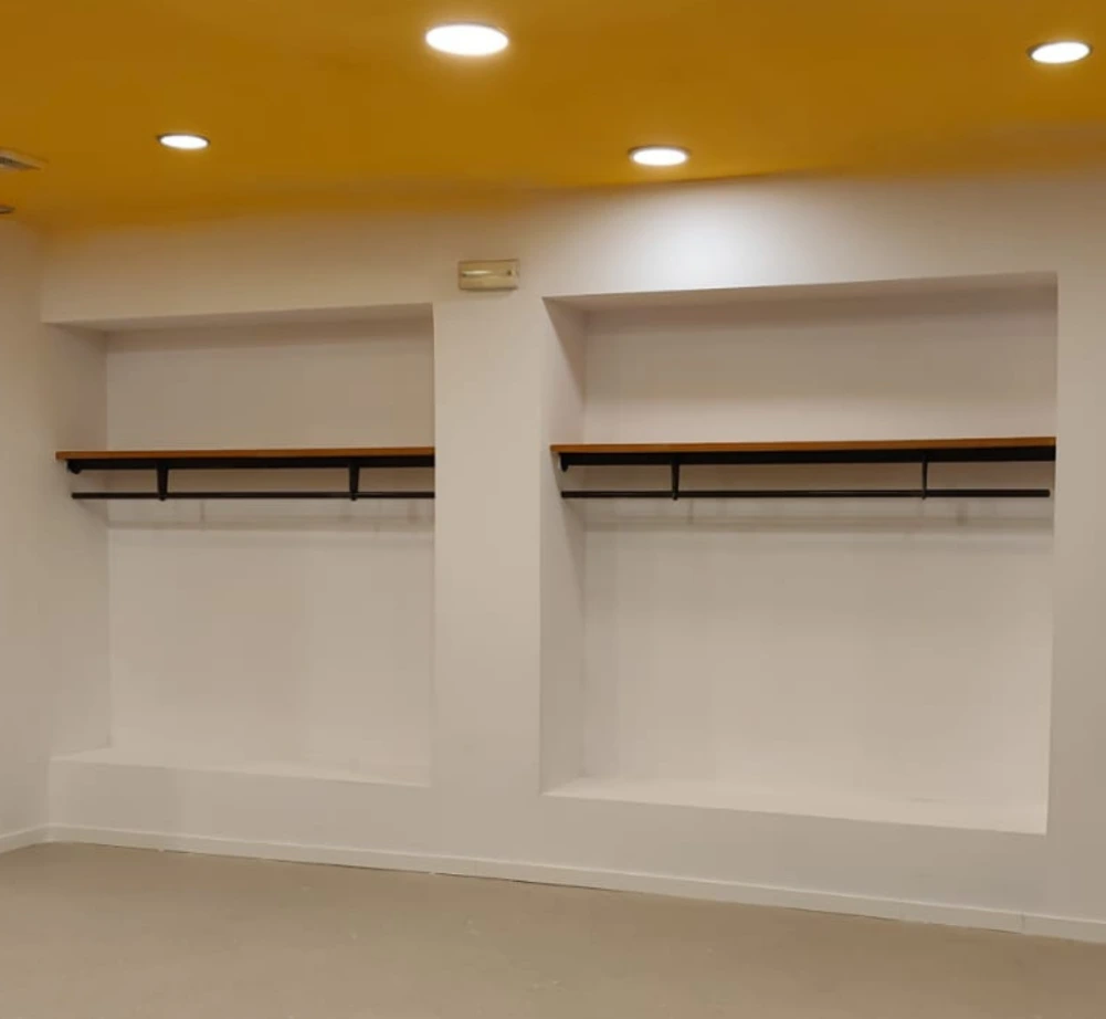 Instalación de pladur con hornacinas decorativas, estantes de madera y techo amarillo en Barcelona
